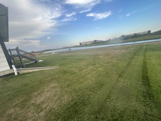 A lawn with fresh mowing stripes overlooking a pond and neighborhood